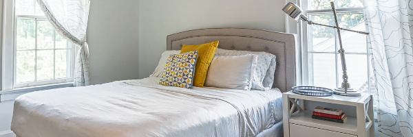 A bed with a bedside table, near the corner of the room