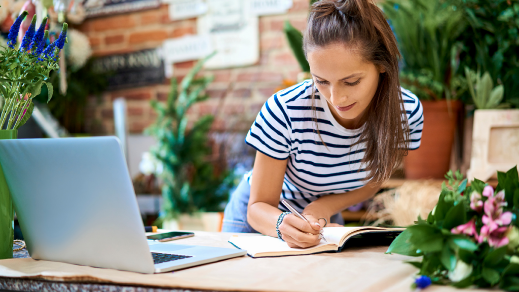 Woman writing in a notebook at a home office desk